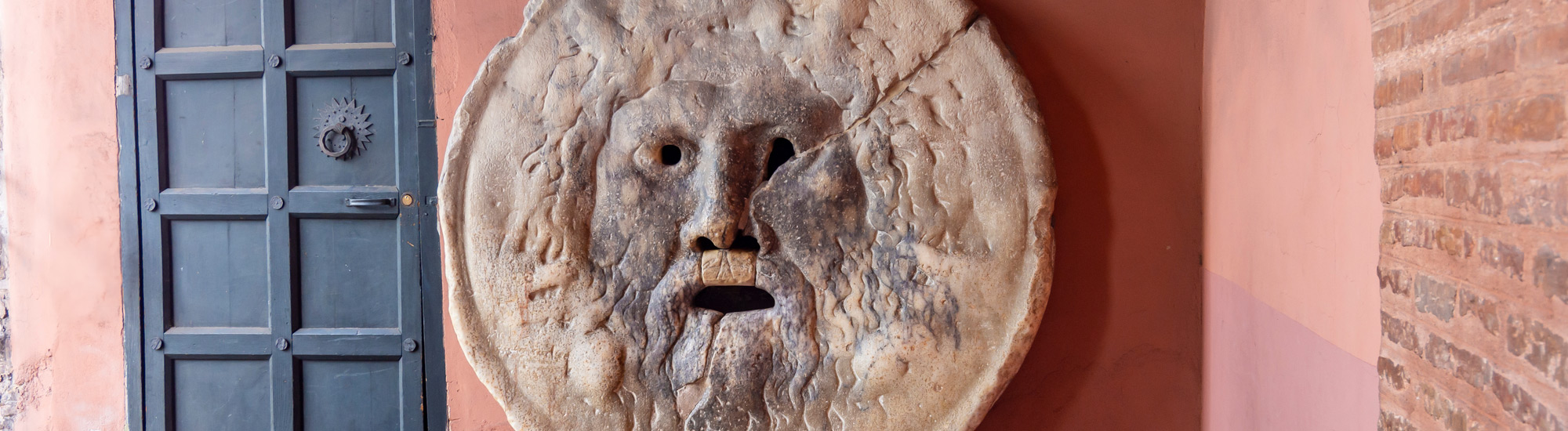 primo piano della famosa pietra (bocca della verità) raffigurante un volto con la bocca a perta,