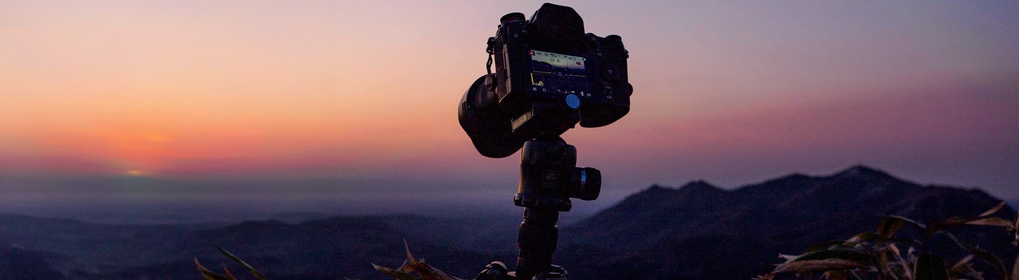 Fotocamera su treppiedi in montagna al tramonto - Foto di ぜつえん da Adobe Stock