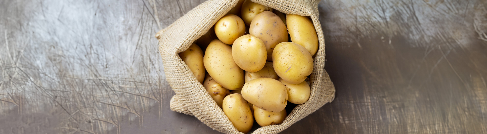 Sacco di patate su tavolo rustico - Foto di Uuganbayar da Adobe Stock