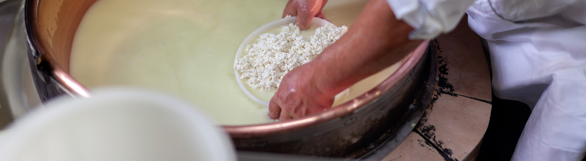 Casaro lavora al pentolone per produrre ricotta - Foto di Fotopogledi da adobe Stock