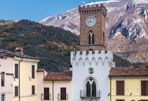Scorcio della piazza principale del borgo, con il campanile e le montagne sullo sfondo
