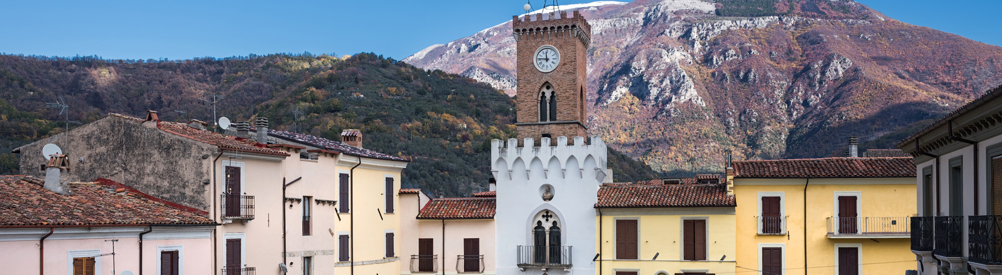 Scorcio della piazza principale del borgo, con il campanile e le montagne sullo sfondo